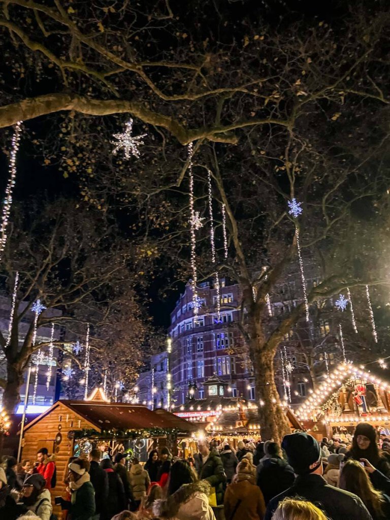 Glühweintrinken unter lichterkettenbehangenen Bäumen am Leicester Square London