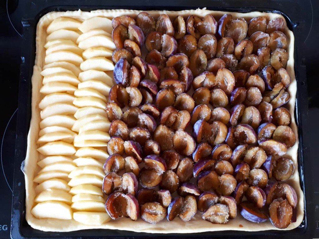 Zwetschgenkuchen im Blech mit ein paar Äpfeln für die Tochter