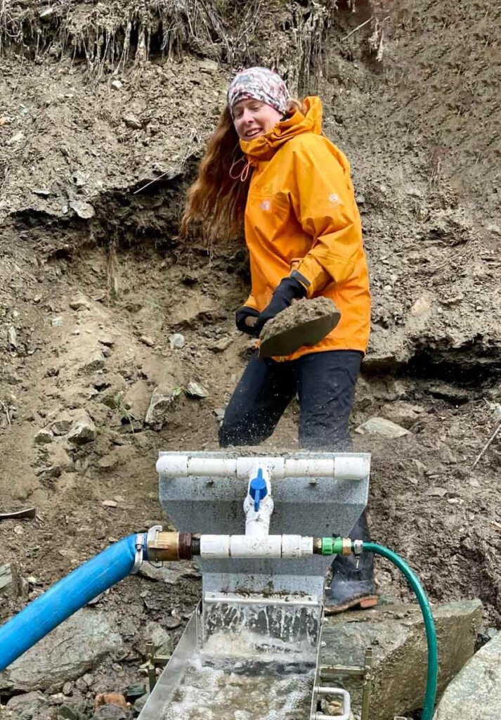 Elke schaufelt Erde in den Highbanker bei der Goldsuche am Klondike